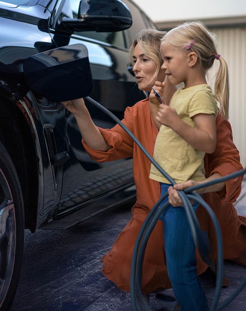 Mutter mit Kind lädt Elektroauto