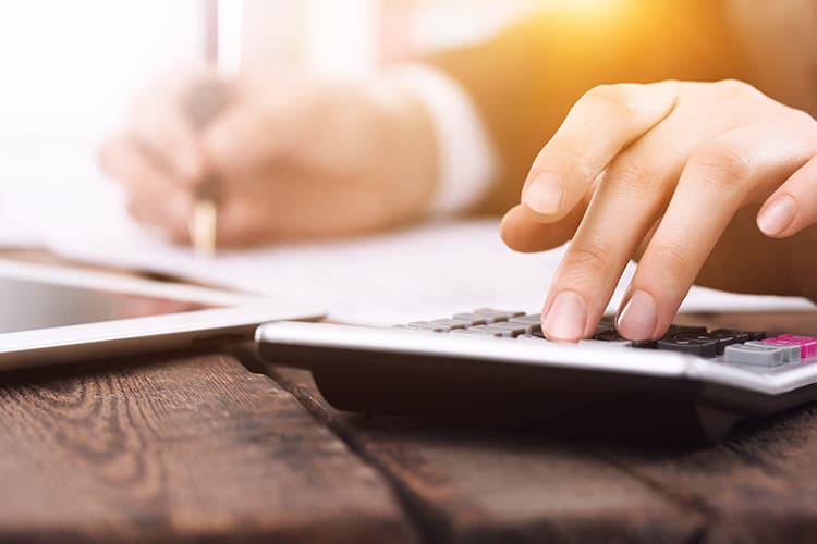 Hand tippt etwas auf Taschenrechner