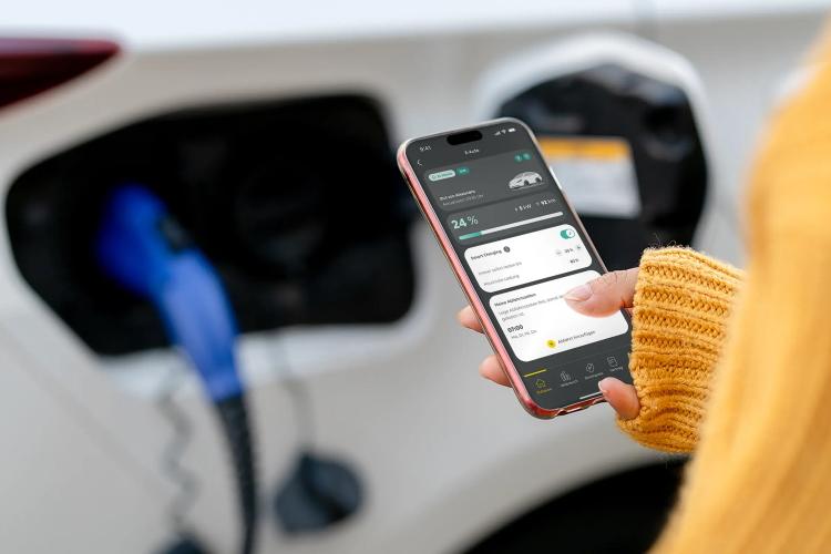 Eine Frau schaut auf die Mein EWE Energie App, während sie ihr Elektroauto lädt
