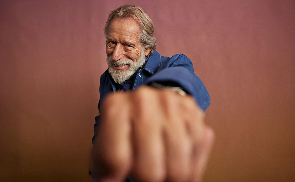 Älterer Herr mit Bart streckt Faust in Richtung der Kamera.