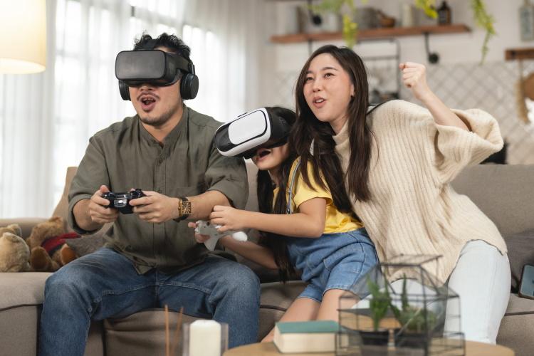 Mutter, Vater und Tochter zocken mit VR-Brille