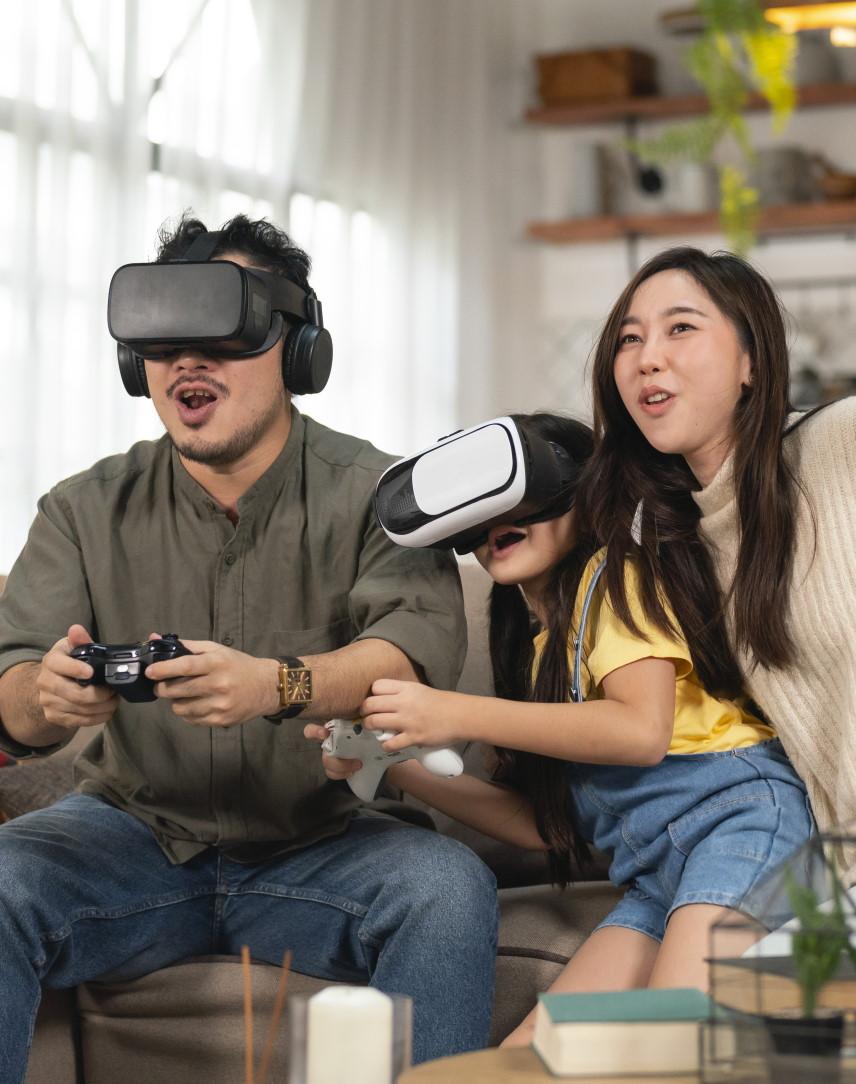 Mutter, Vater und Tochter zocken mit VR-Brille