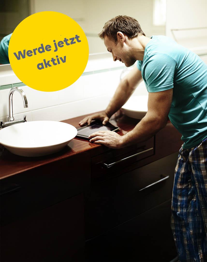 Mann schaut im Badezimmer auf Tablet
