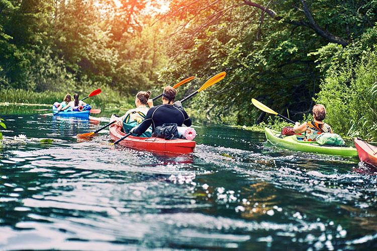Gruppe junger Leute beim Kajakausflug und Rafting auf dem Fluss in Haselünne