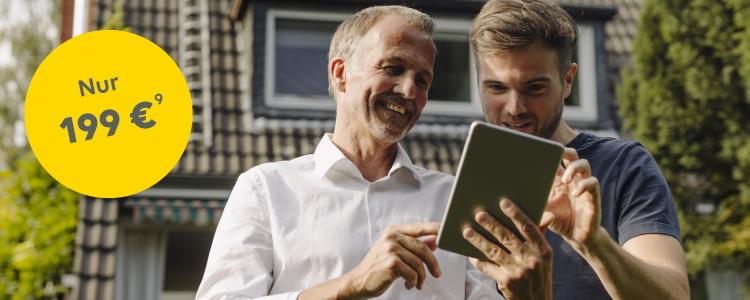 Zwei Männer schauen vor einem Haus gut gelaunt auf ein Tablet, ein gelber Störer weist den Preis von nur 199 Euro für den Gebäudecheck aus