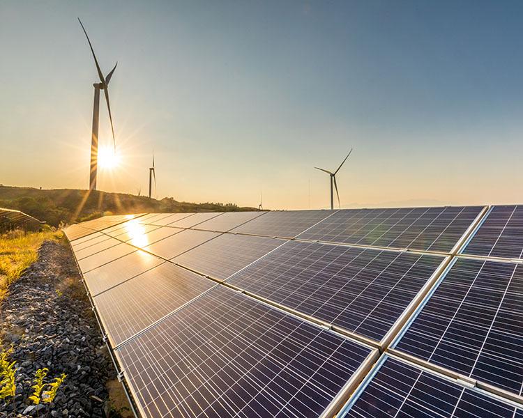 Photovoltaikanlage auf einem Feld und Windanlagen im Hintergrund