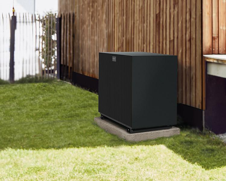 Wärmepumpe vor einem Holzhaus