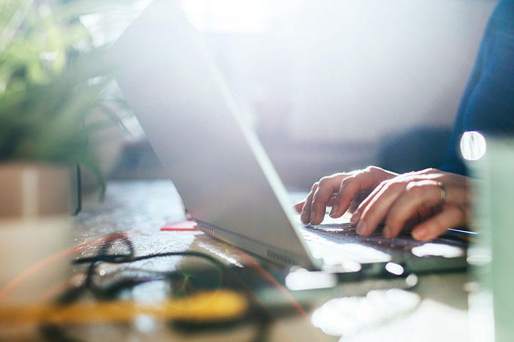 Zwei Hände tippen auf Laptop