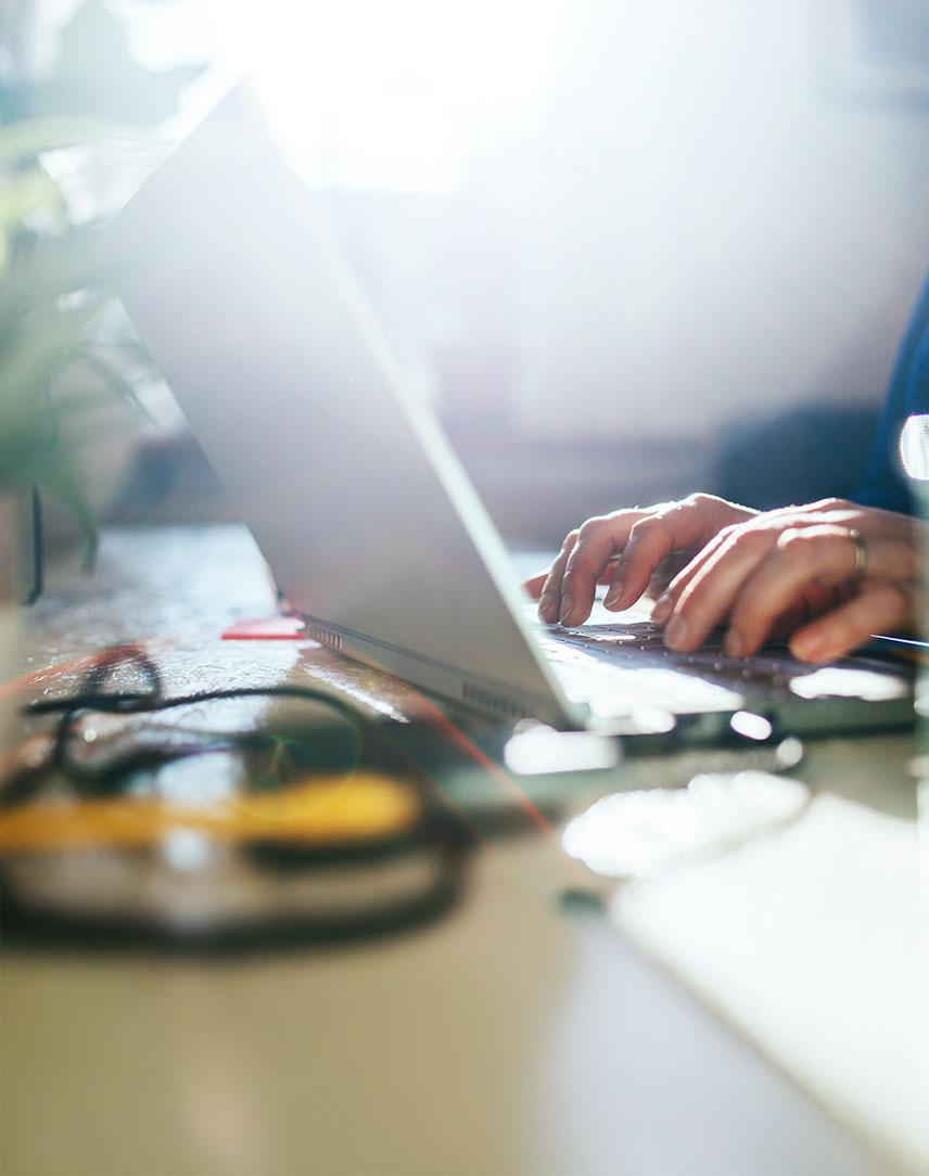 Zwei Hände tippen auf Laptop