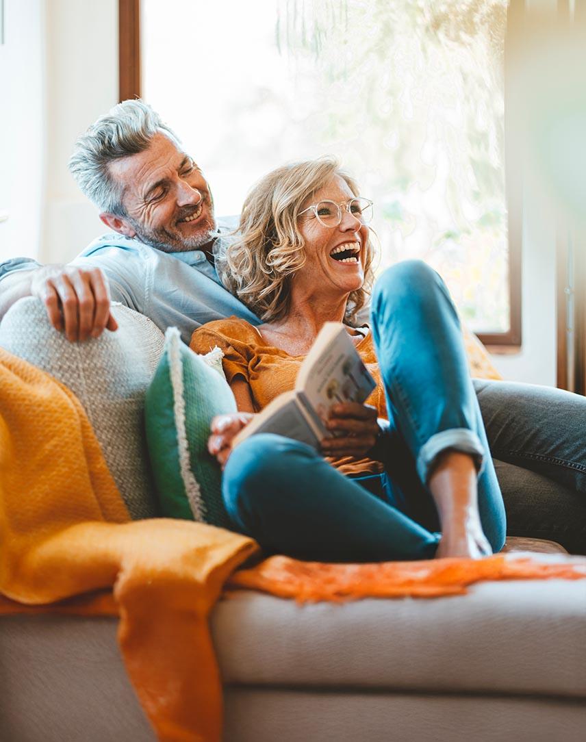 Pärchen auf dem Sofa mit Buch in der Hand freut sich