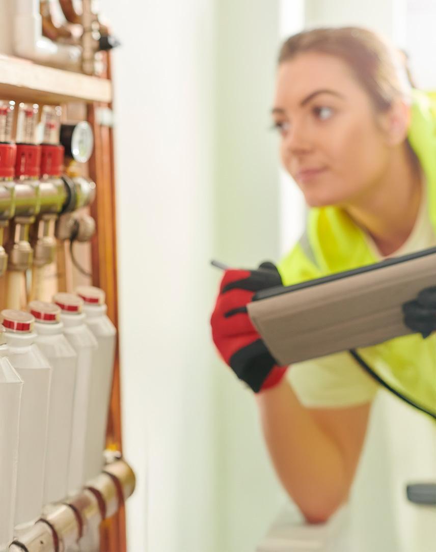 Frau mit Warnweste prüft Heizung