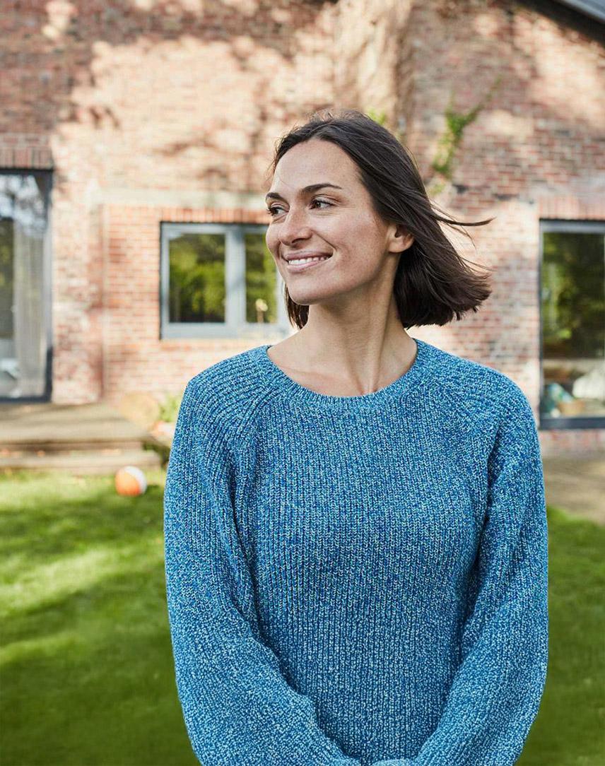 Lächelnde Frau im Garten vor einem Wohnhaus