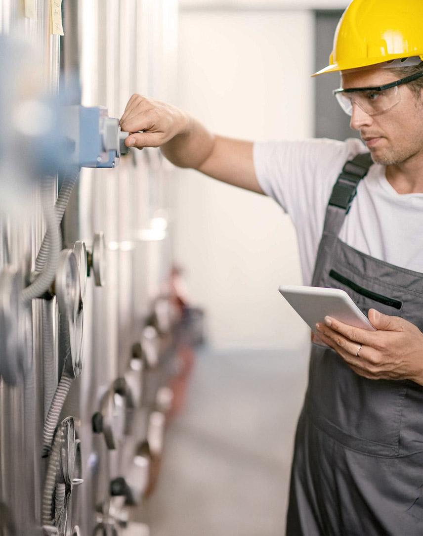 Mann mit Bauhelm prüft Heizung