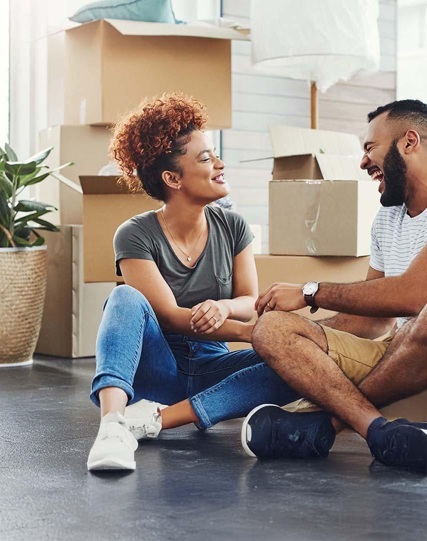 Lachendes Pärchen sitzt vor Umzugskantons auf dem Boden