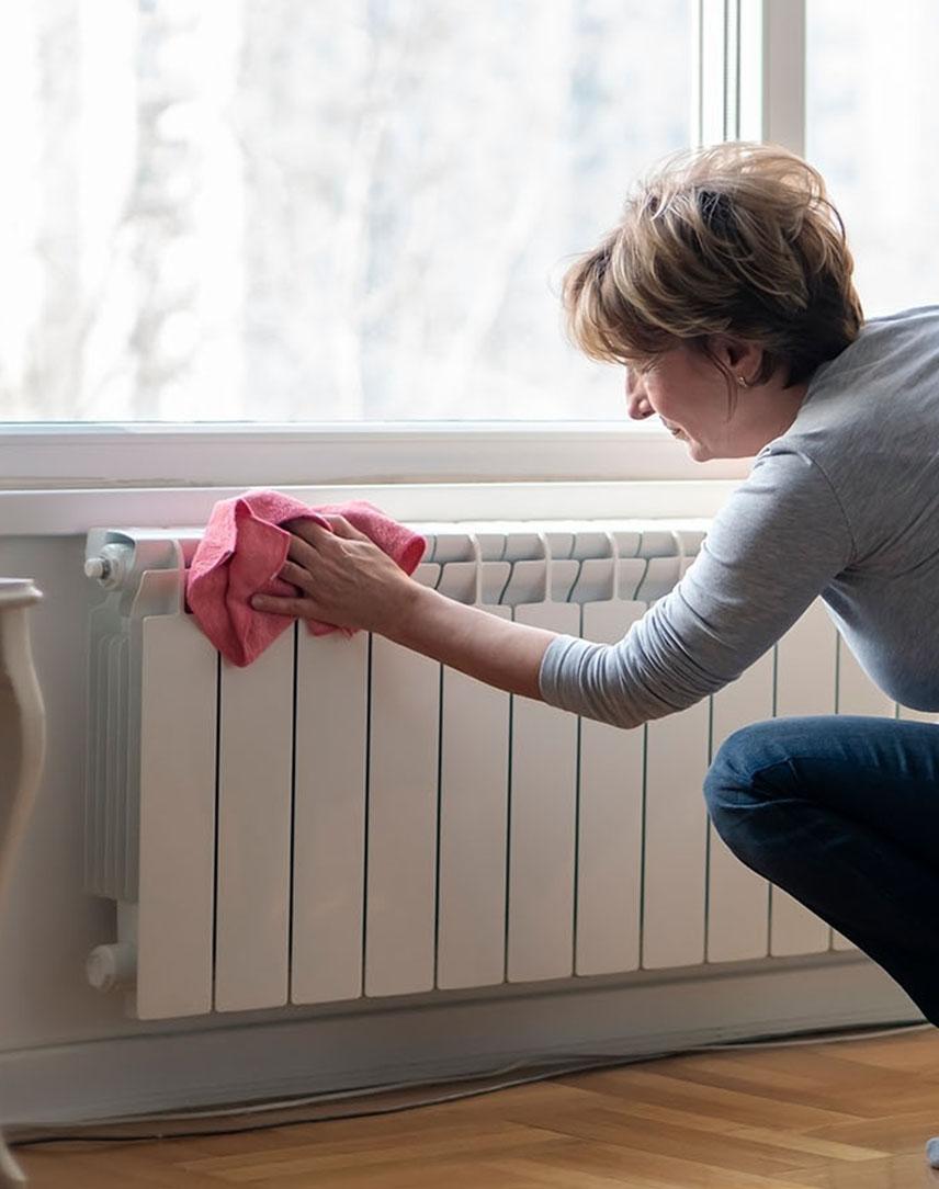 Frau putzt mit Lappen die Heizung