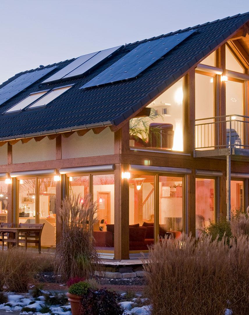 Von innen beleuchtetes Haus mit Solaranlage auf dem Dach