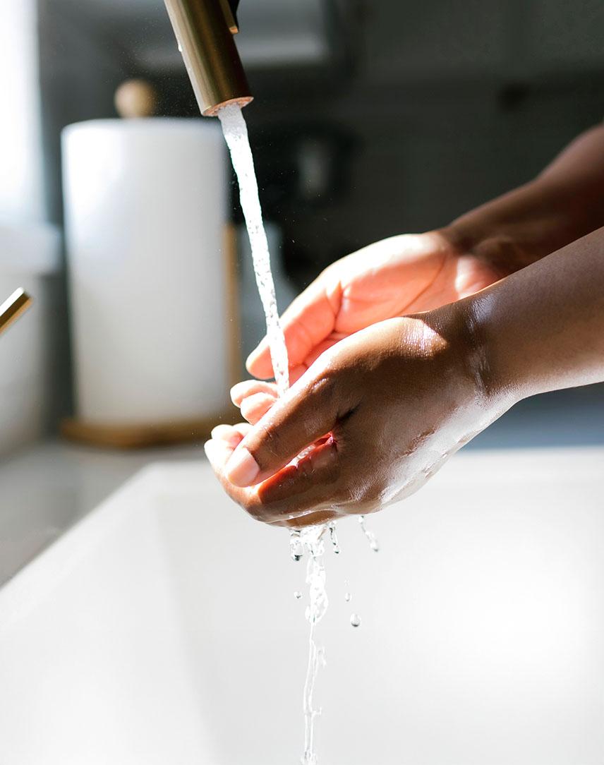 Zwei Hände unter dem Strahl eines Wasserhahns