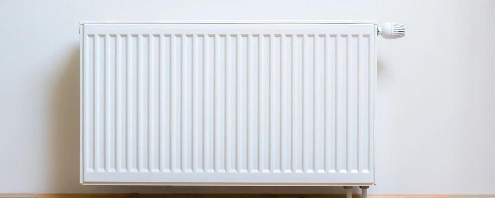 Weißer Plattenheizkörper vor weißer Wand