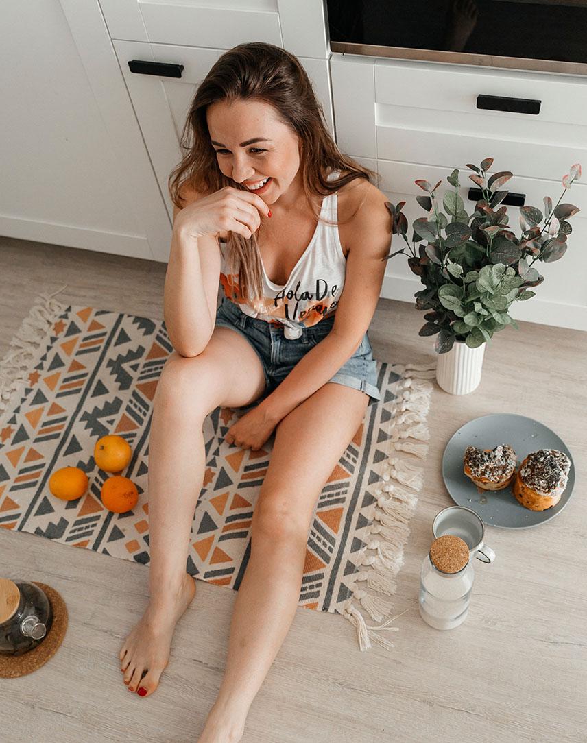 Glückliche Frau sitzt auf einem Teppich auf dem Boden