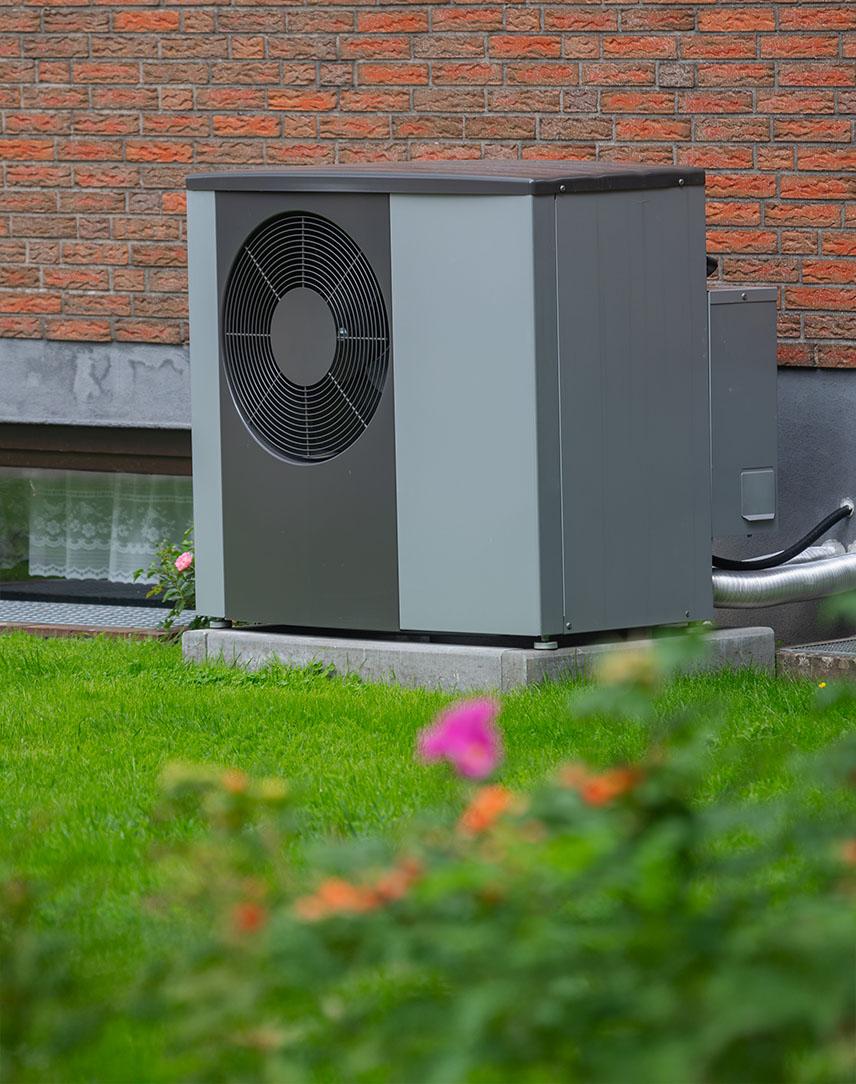 Dunkle Wärmepumpe vor einer Hauswand