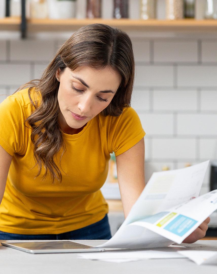 Frau in der Küche liest sich Unterlagen durch