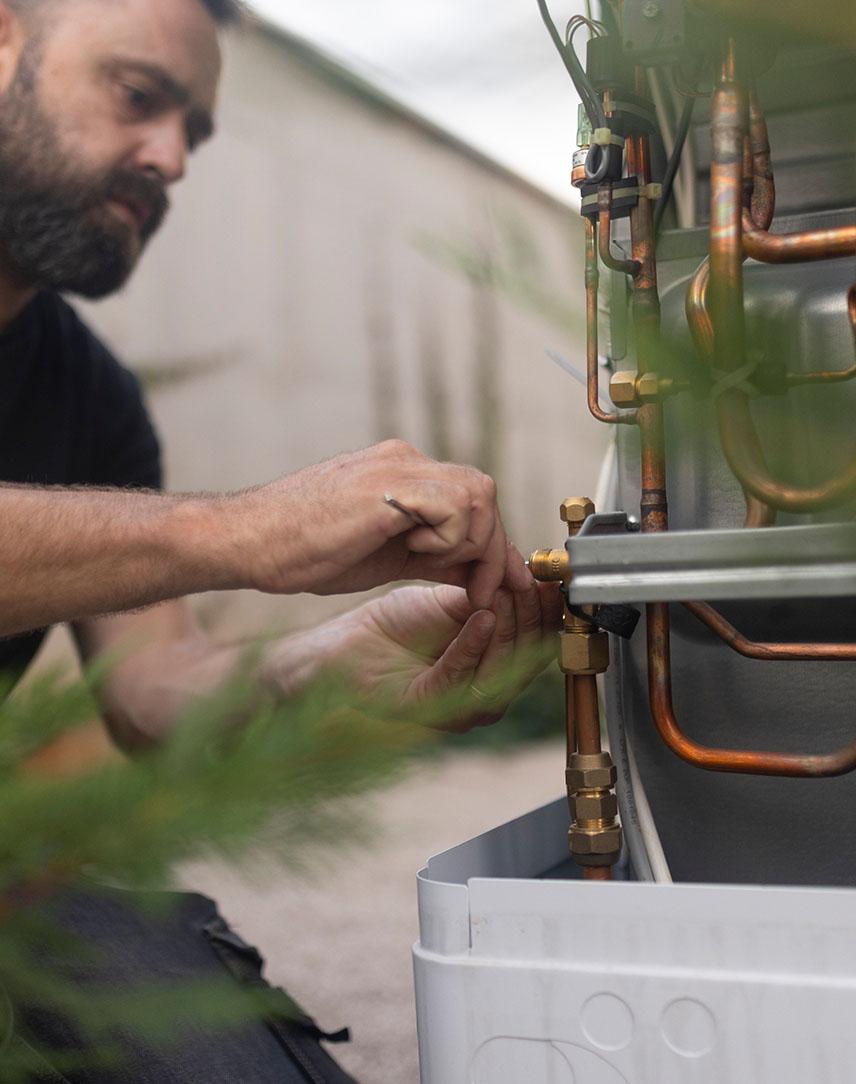 Mann mit Bart arbeitet an einer Wärmepumpe