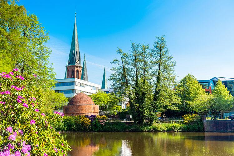 Blick auf die St. Lamberti Kirche in Oldenburg. Im Vordergrund befindet sich der Schloßteich und der Oldenburger Pulverturm.